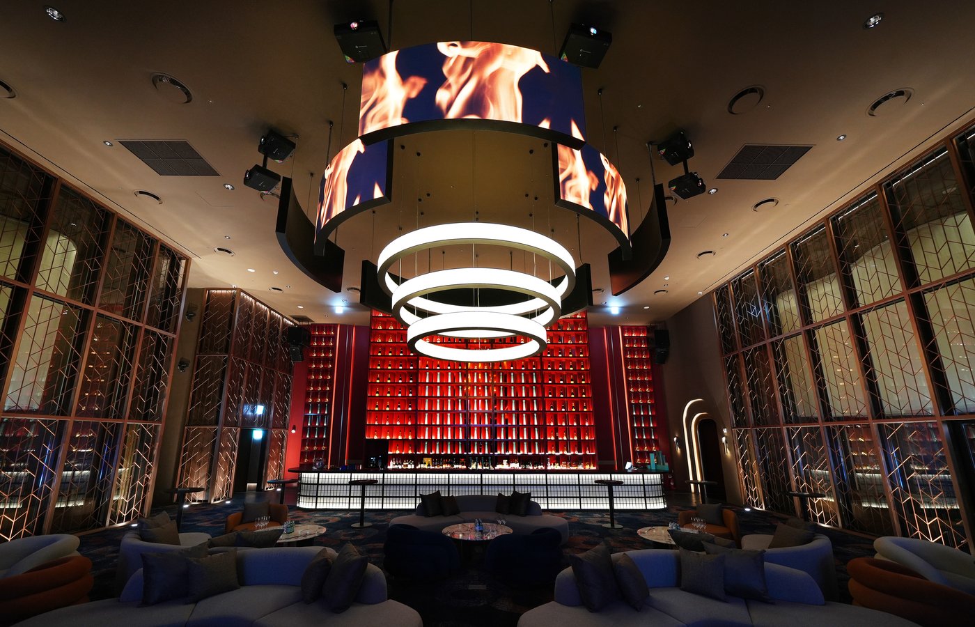 A striking centerpiece bar at Ultra Lounge, featuring dramatic red backlighting, a sculptural LED chandelier, and a refined atmosphere designed for high-energy nights and elevated social experiences.