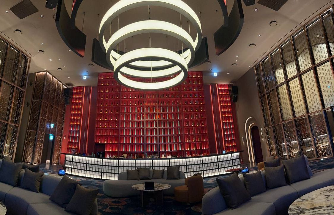 Sweeping ceilings, glowing chandeliers, and a striking red bottle wall define the Ultra Lounge bar—a dramatic, high-end setting built for VIP nights at INSPIRE.